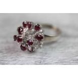 Ruby and diamond 14ct white gold fancy cluster ring comprising twelve oval mixed cut claw set rubies