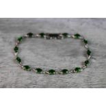 Chrome diopside 9ct white gold line bracelet, comprising fifteen oval mixed cut chrome diopside,