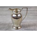 Silver cream jug of plain form, ribbed decoration to foot and rim, stepped angular handle,