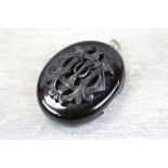 Large jet oval locket pendant with applied monogram to centre, plain reverse, glazed compartments to