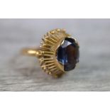 Synthetic colour change sapphire sunburst 18ct yellow gold ring, the central oval mixed cut stone