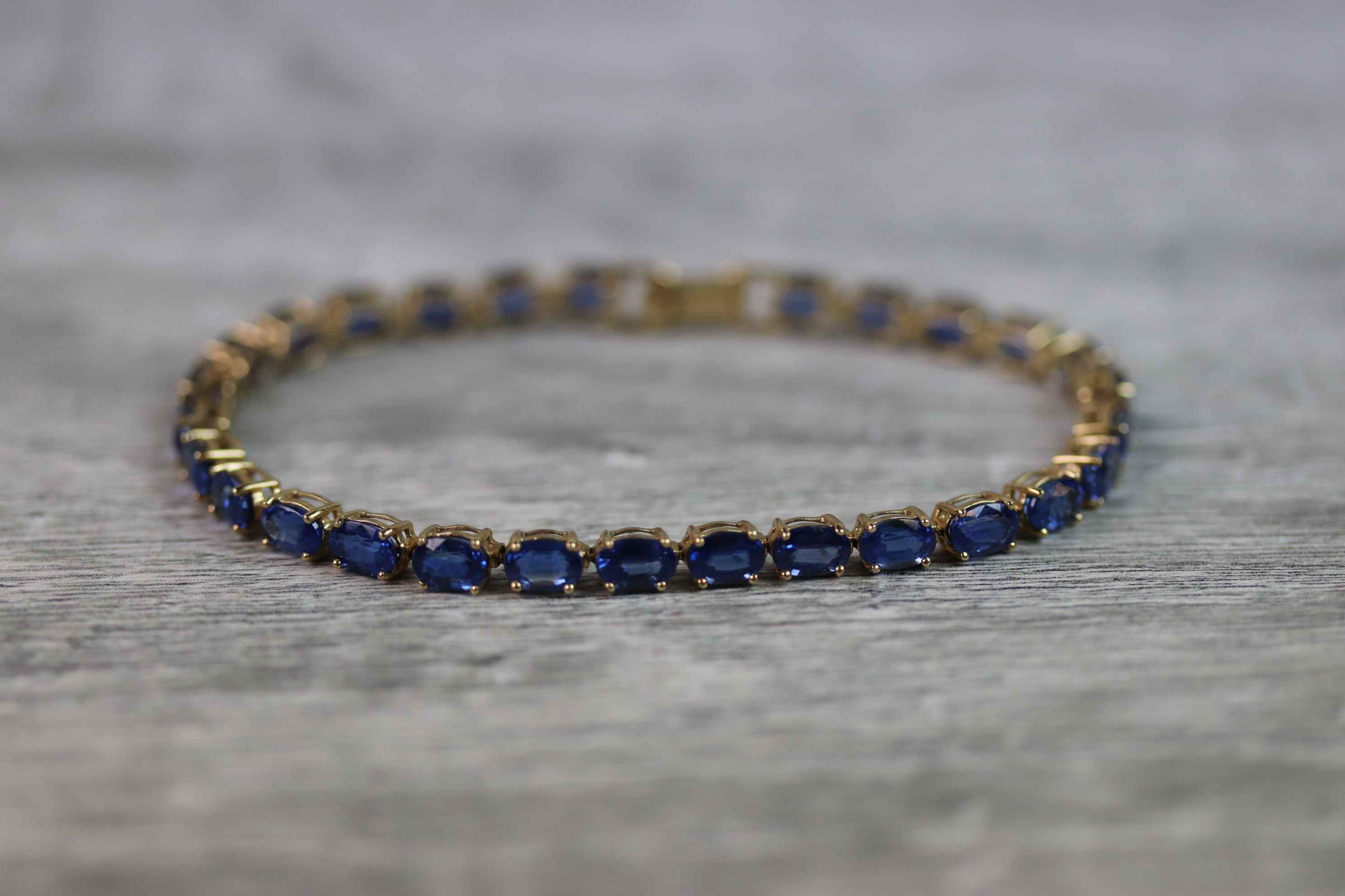 Kyanite 9ct yellow gold line bracelet comprising twenty-eight oval mixed cut kyanite, each kyanite