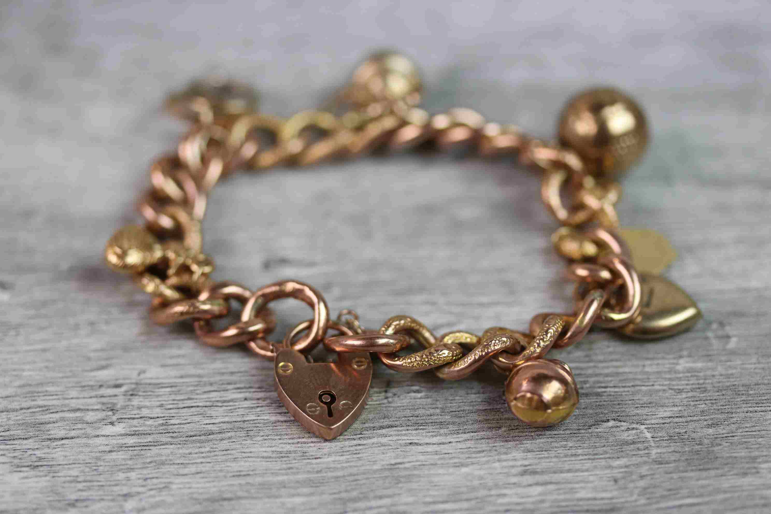 9ct rose gold curb link charm bracelet with 9ct rose gold padlock clasp, seven 9ct gold and yellow - Image 2 of 10
