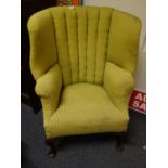 Yellow upholstered club chair with arched high back on pad supports, Queen Anne style