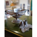Silver coloured small basket and a silver coloured toy size leaf shaped candle holder with snuffer