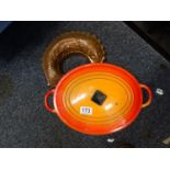 Le Cruset, an orange cast metal oval casserole dish nd lid and a copper food mould modelled as a