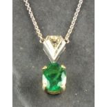 An emerald and diamond pendant, the oval claw set stone with a trillion cut bail, on a fine link
