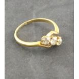 A three stone diamond ring, the cross-over setting in an 18ct gold band, 2.8g
