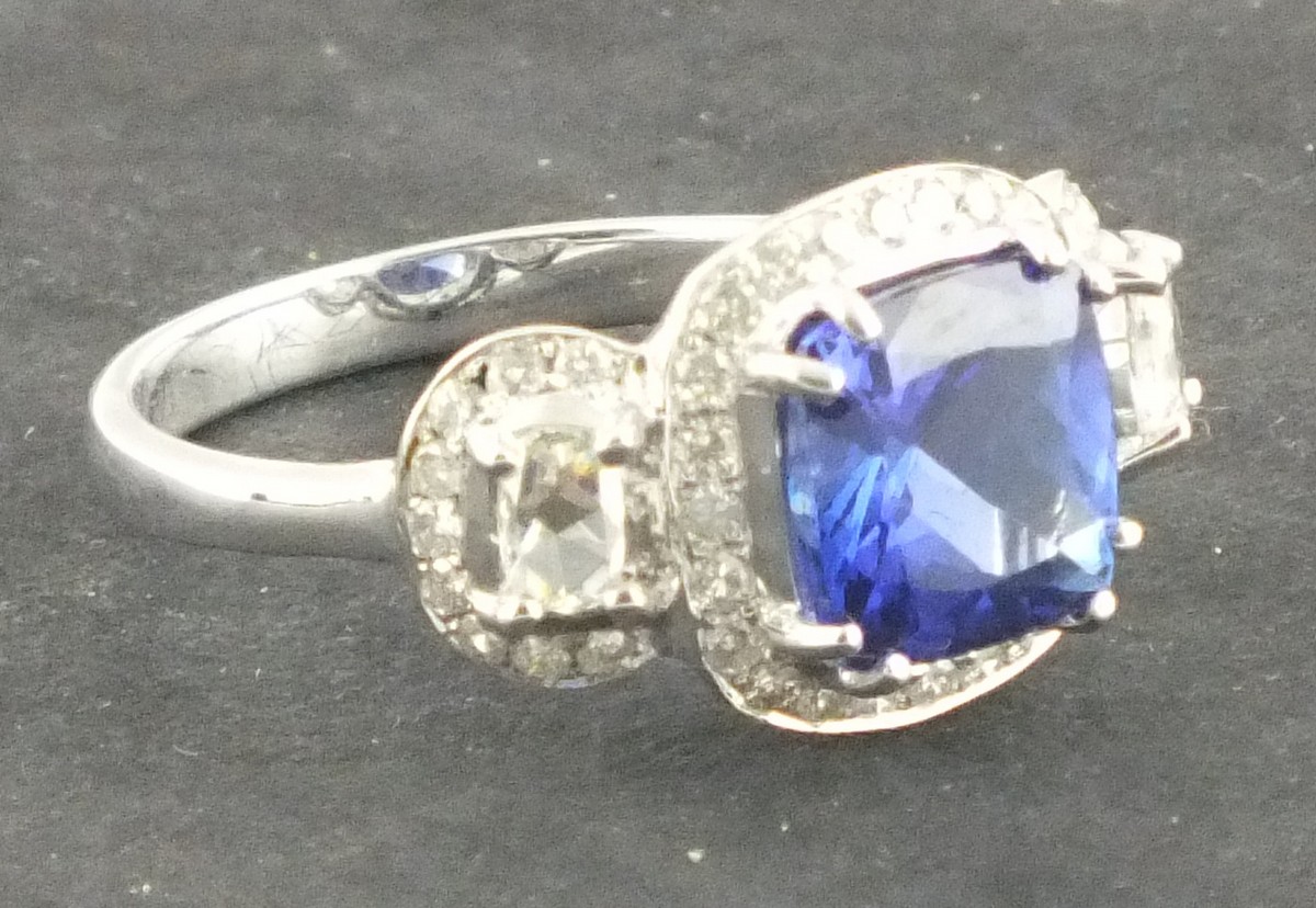 A tanzanite and diamond dress ring, the central emerald cut stone approx 2.84ct within a band of