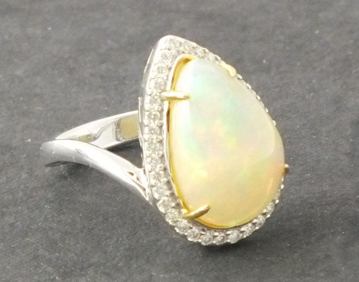 An opal and diamond cluster ring, the pear shaped central stone approx, 4.4ct within a band of