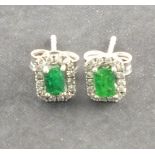 A pair of emerald and diamond ear studs, the emerald cut stones within a band of diamonds, 1.6g