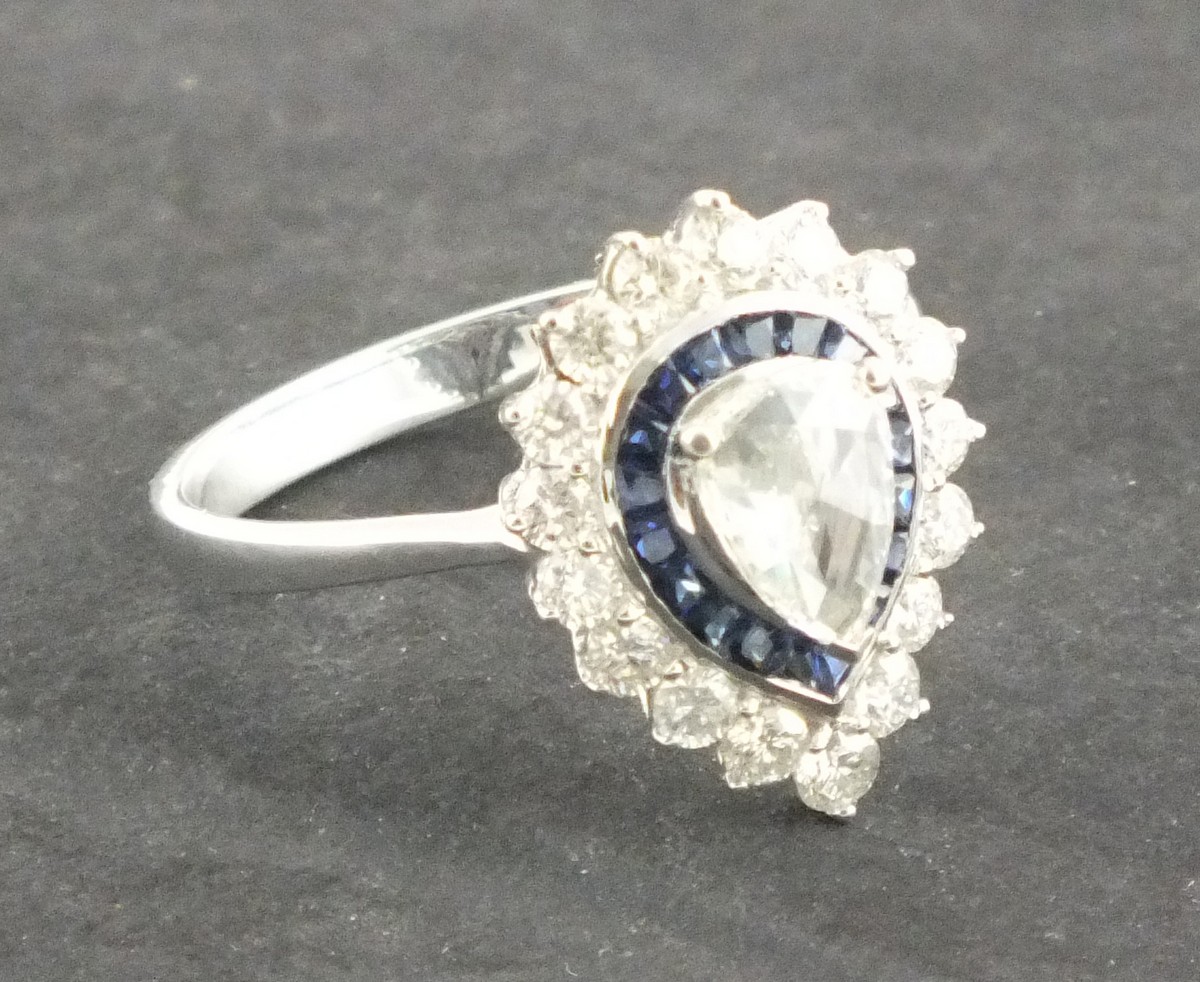 A sapphire and diamond dress ring, the pear shaped central stone within a band of sapphires and