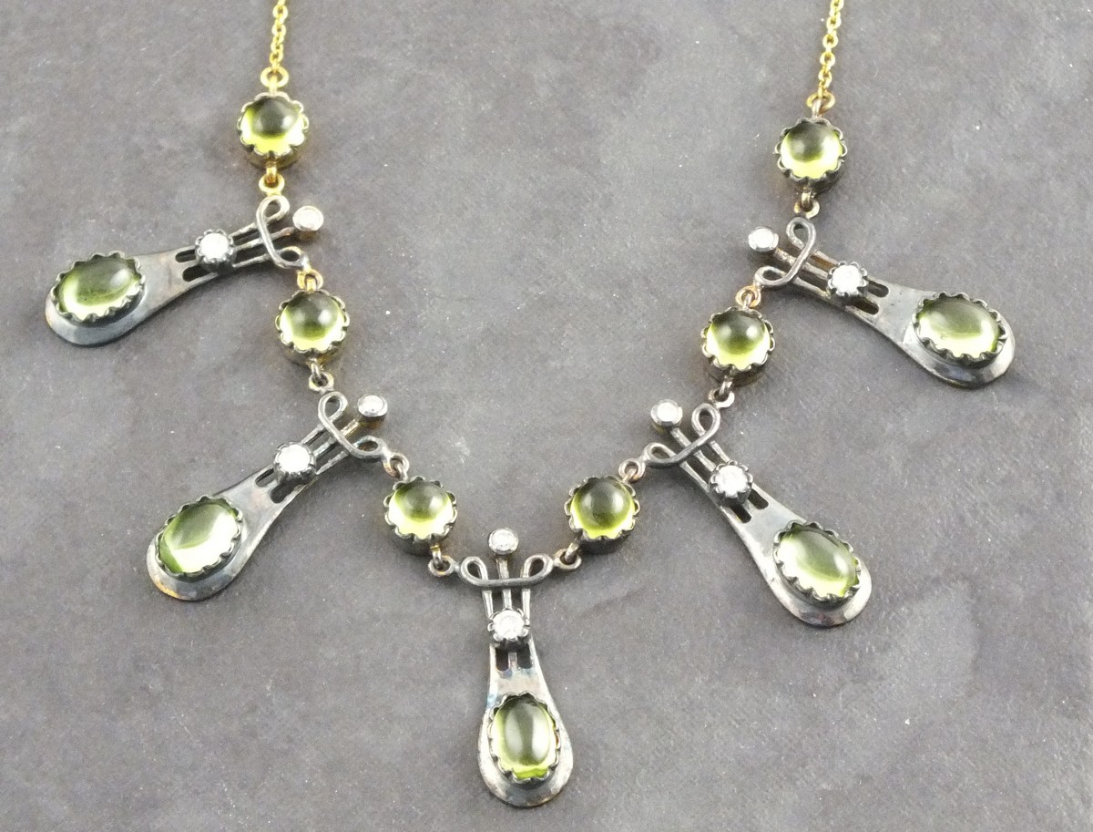 A peridot and diamond fringe necklace, the cabochon stones mounted in pendents and suspended from
