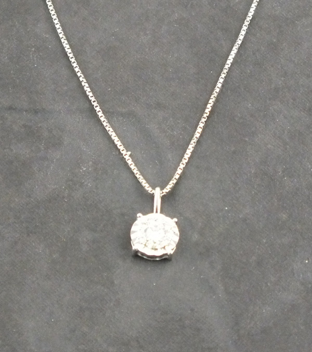 A diamond cluster pendent, the stones set in an 18ct white gold frame, on a fine silver chain, 2.6g