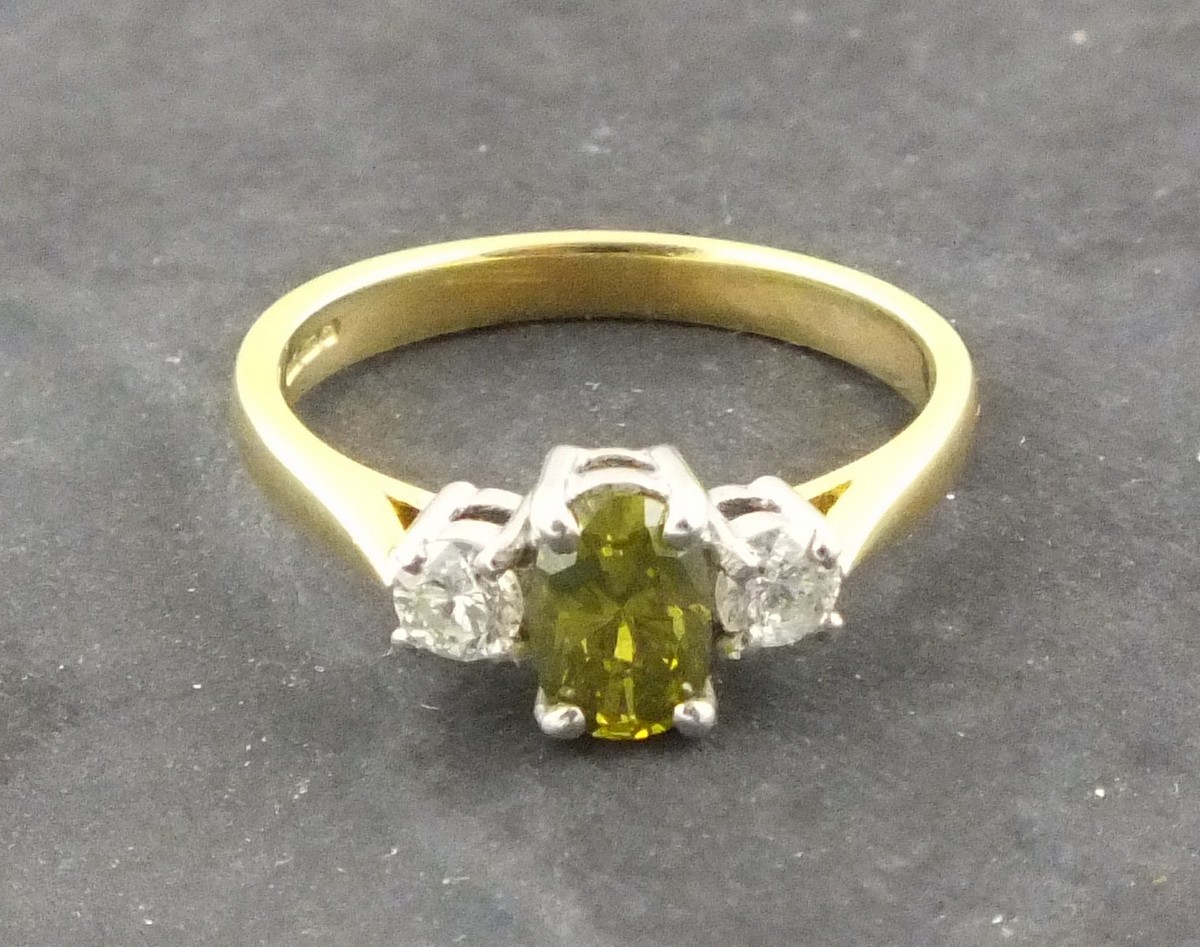 A three stone diamond ring, the central fancy green/yellow baguette cut stone (treated) 0.65ct