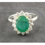 An emerald and diamond dress ring, the oval central stone, 3ct, claw set within a band of