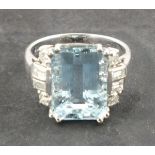 An aquamarine and diamond set dress ring, the enrald cut central stone 6.65ct flanked by baguette