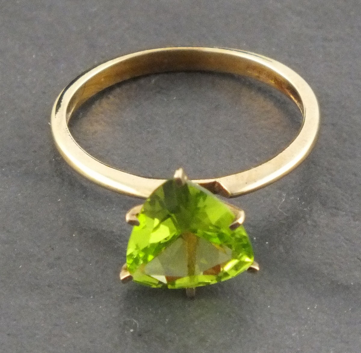 A 9ct gold and peridot ring, the trillion cut stone within a claw setting, size N