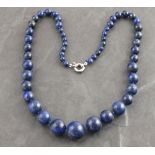 A lapis lazuli necklace, of graduated beads, 23" (58cm) long,