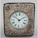 A silver repousse timepiece, London 1980, the foliate decorated front on a blue velvet case about an
