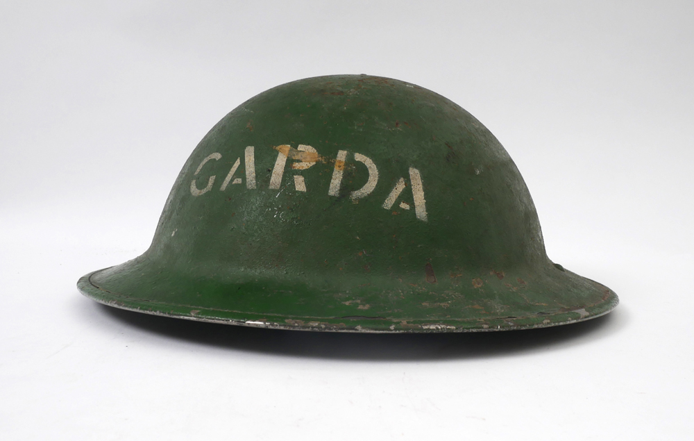 Garda Siochana steel helmet. A British 'Tommy' helmet, painted green and stencilled 'GARDA' in