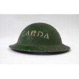 Garda Siochana steel helmet. A British 'Tommy' helmet, painted green and stencilled 'GARDA' in