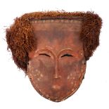 Tribal mask, Lega, Congo. A painted carved wood mask, the red face with white and pink spots,