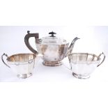 An Art Deco silver three-piece tea service. The faceted body engraved with a band of geometric