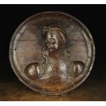 A Stained Pine Roundel carved in relief with the bust of a Renaissance lady,