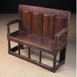 A Late 16th Century Panelled Oak Child's Settle with four fileded panels to the back and long seat