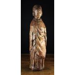 A 14th Century Wood Carving of a Saint wearing a mitre and draped robes, his eyes lowered,