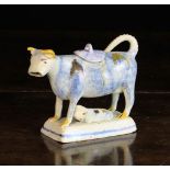 A 19th Century Cow Creamer decorated with sponged blue and daubed ochre & brown glaze and modelled