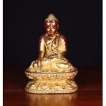 A Gilded Cinnabar Lacquered Wood Carving of a Seated Buddha, 13½ in (34 cm) in height.