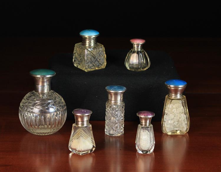 Seven Pretty Cut Glass Scent Bottles with silver & guilloche enamelled lids.