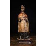 A 17th/18th Century Carving of a Priest wearing a biretta, shoulder cap and draped tunic,