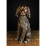 A Late 19th/Early 20th Century Folksy Wood Carving of a seated Spaniel, 17¾ in (45 cm) in height.