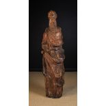 A Tall 17th Century Carved Wooden Sculpture of a bearded monk in draped robes, with hollowed back,