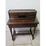 A 19th century inlaid rosewood bonheur de jour with a brass gallery on five drawer upstand with a