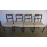 A set of four mahogany framed dining chairs with overstuffed seats and raised on turned supports