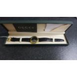 A gold plated cased Gucci wristwatch with black dial, Roman numeral hour markers to bezel - in