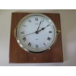 A Stockburger ships bulkhead clock in circular brass case on wooden mount with quartz movement