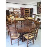 An antique style oak gate leg table with 8 ladder back chairs including two carvers with rush