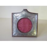 A silver hallmarked picture frame with embossed decoration and central circular aperture