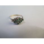 A 19ct yellow gold diamond and emerald ring with sixteen stones set in four rows - size U - approx 2