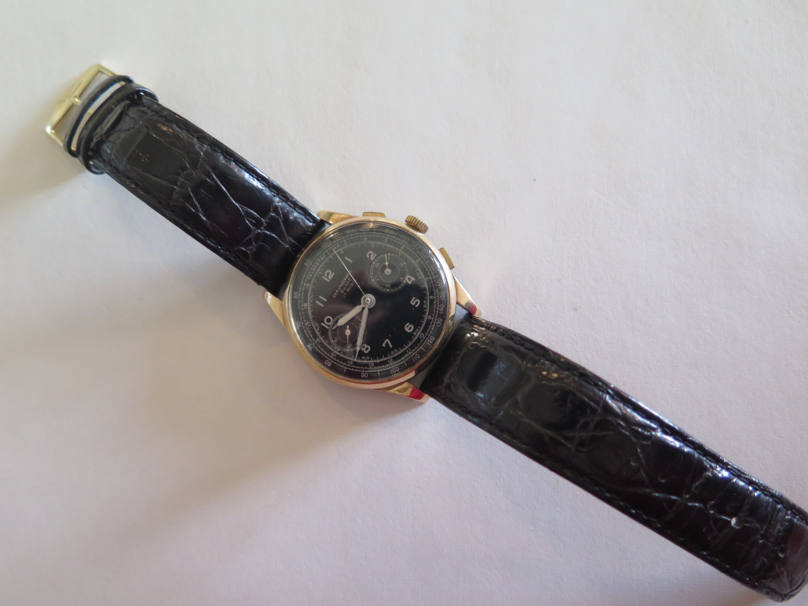 A gents 18ct gold chronograph wrist watch, the black dial with white markers and twin subsidiary