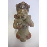 A Pre-Columbian or later polychrome figure with turban and ear spools, holding a bird, 18cm tall,