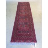 A hand knotted wooden runner with a red field 84 cm x 300 cm