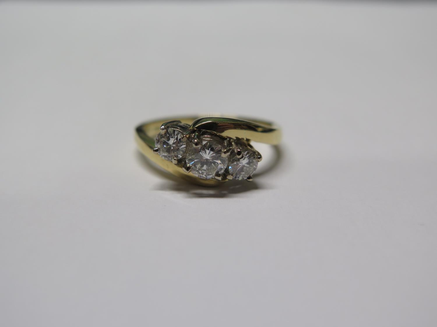 An 18ct yellow and white gold three stone crossover style ring - claw set with brilliant cut