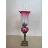 A pipe oil lamp with etched cranberry shade and cranberry reservoir, 51cm tall, small chip to