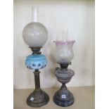 Two oil lamps, one with a swirl pattern glass font and reproduction shade, 58cm tall, and another